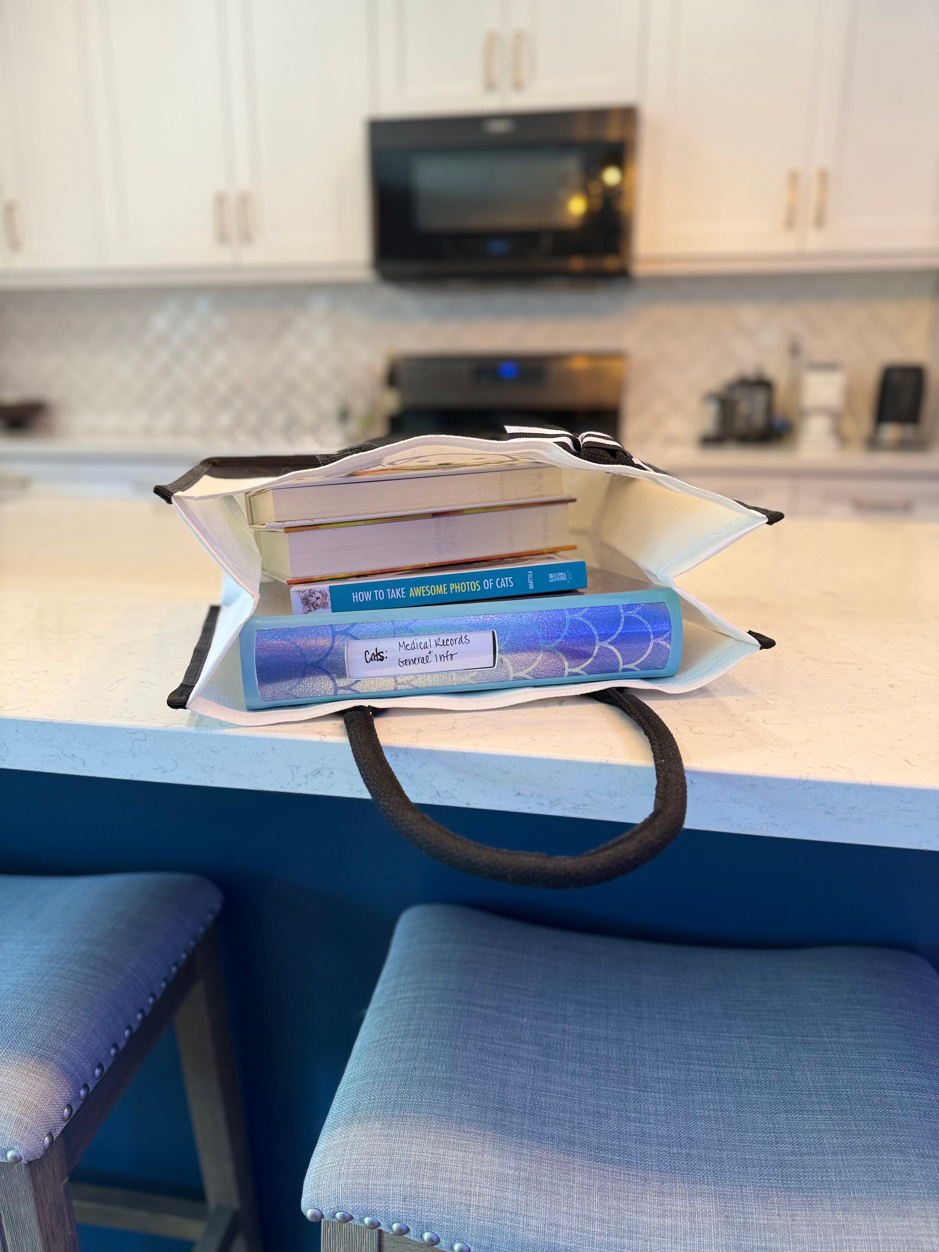 Superior Feline Tote Bag laying on it's side on a kitchen counter with books and a binder inside