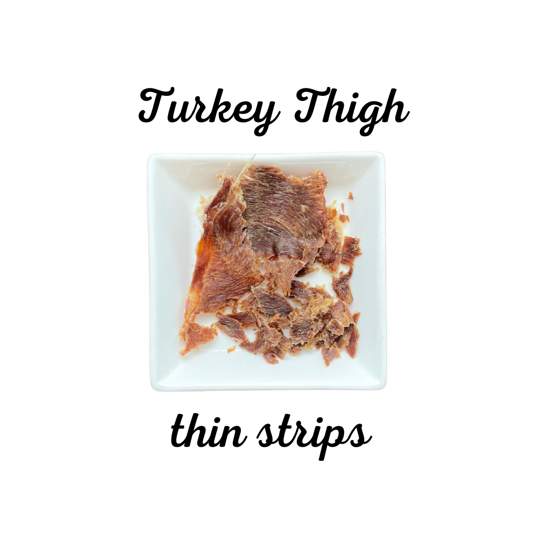 Thin strips of dehydrated turkey thigh on a white plate with text indicating the type of meat